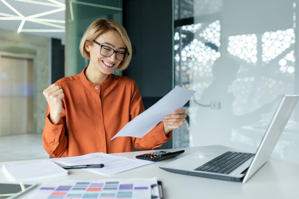 Young happy and successful female financier inside the office at the workplace is satisfied with